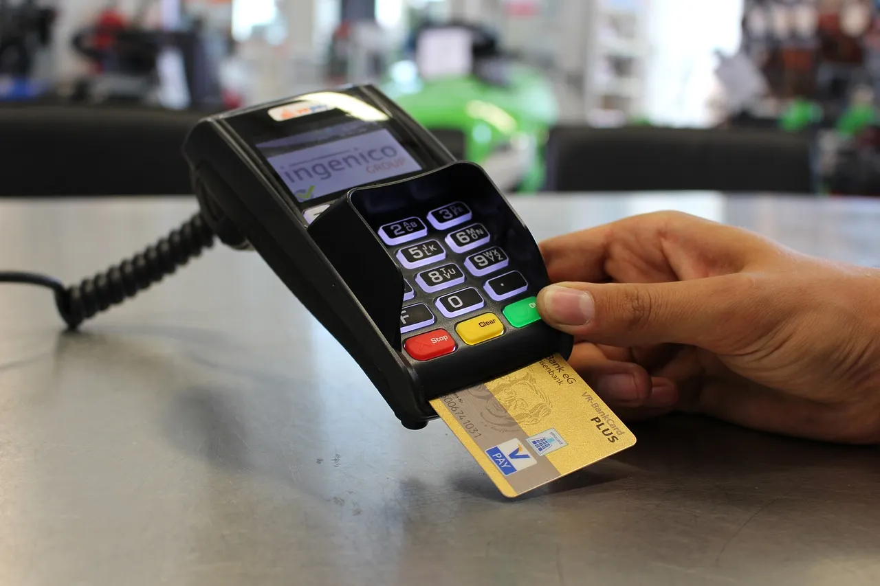 #FotoDescrição: Uma mão inserindo um cartão de crédito em uma máquina de pagamento, simbolizando o uso de pagamentos digitais.