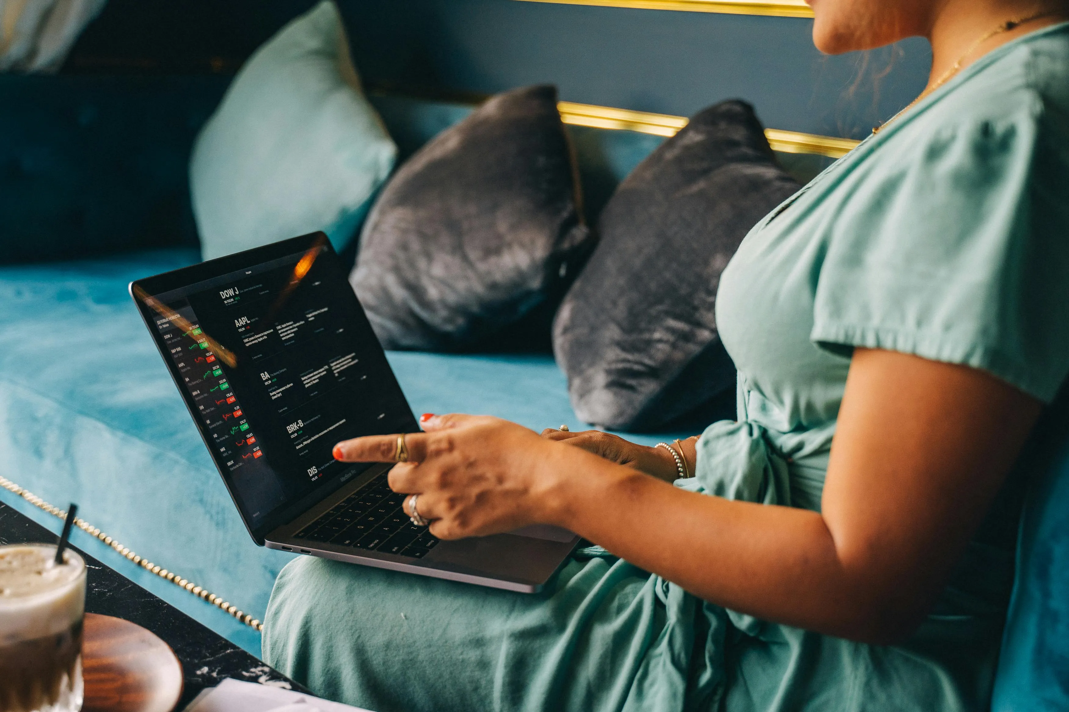 #FotoDescrição: Mulher sentada em um sofá usando laptop com interface de gráfico na tela.