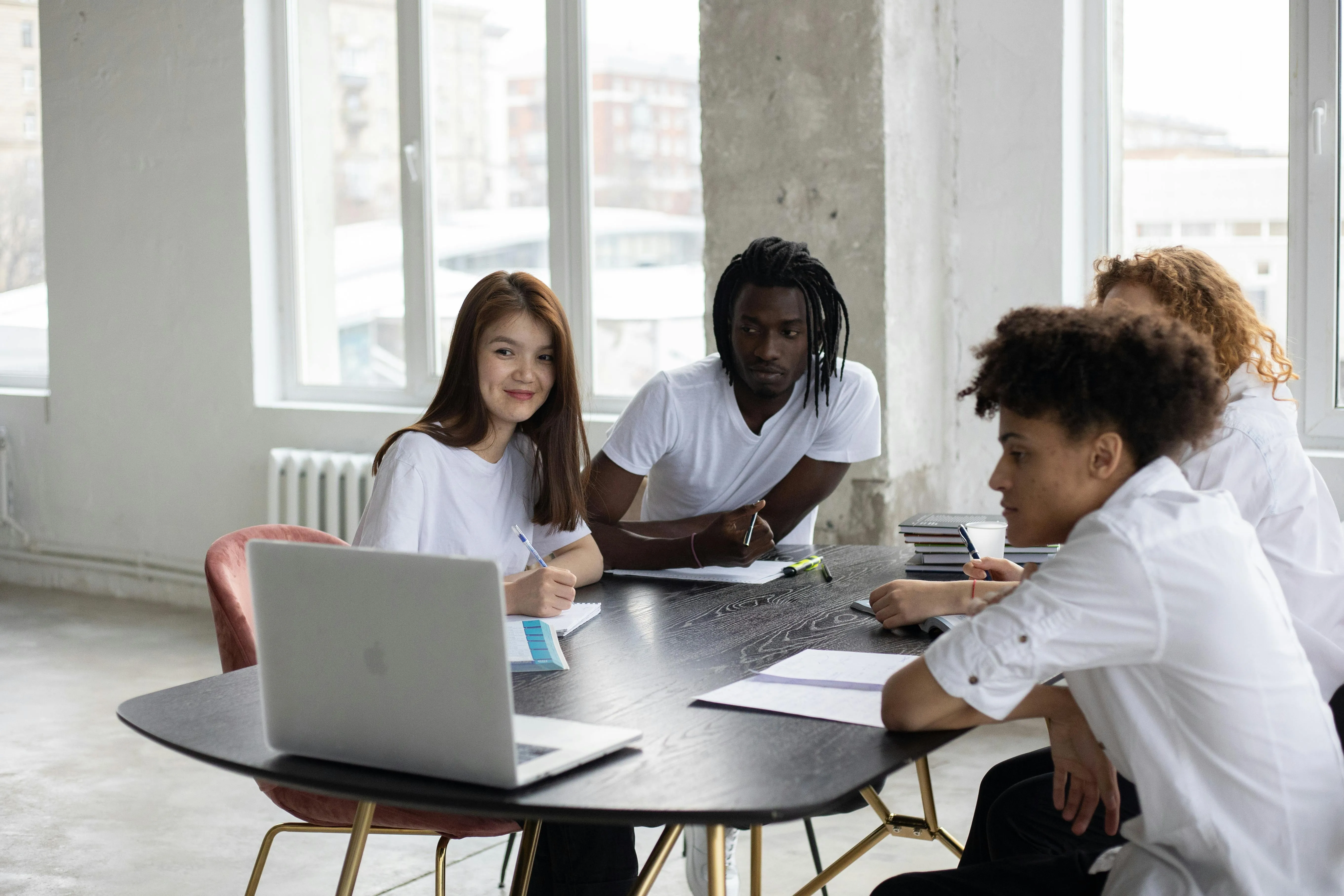 Jovens estudando juntos ao redor de uma mesa com laptop.