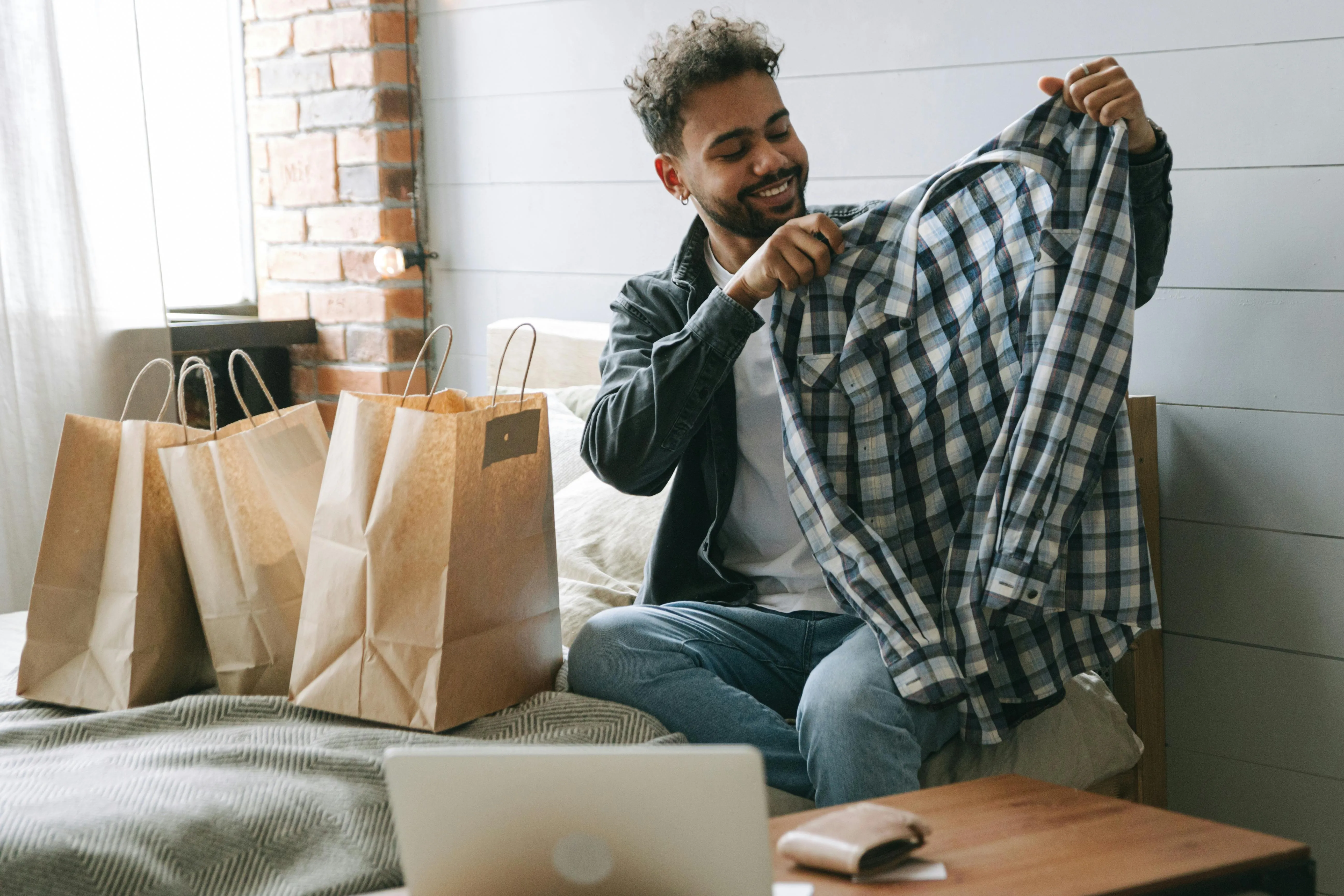 Pessoa mostra camisa recém-comprada ao lado de sacolas de compras.