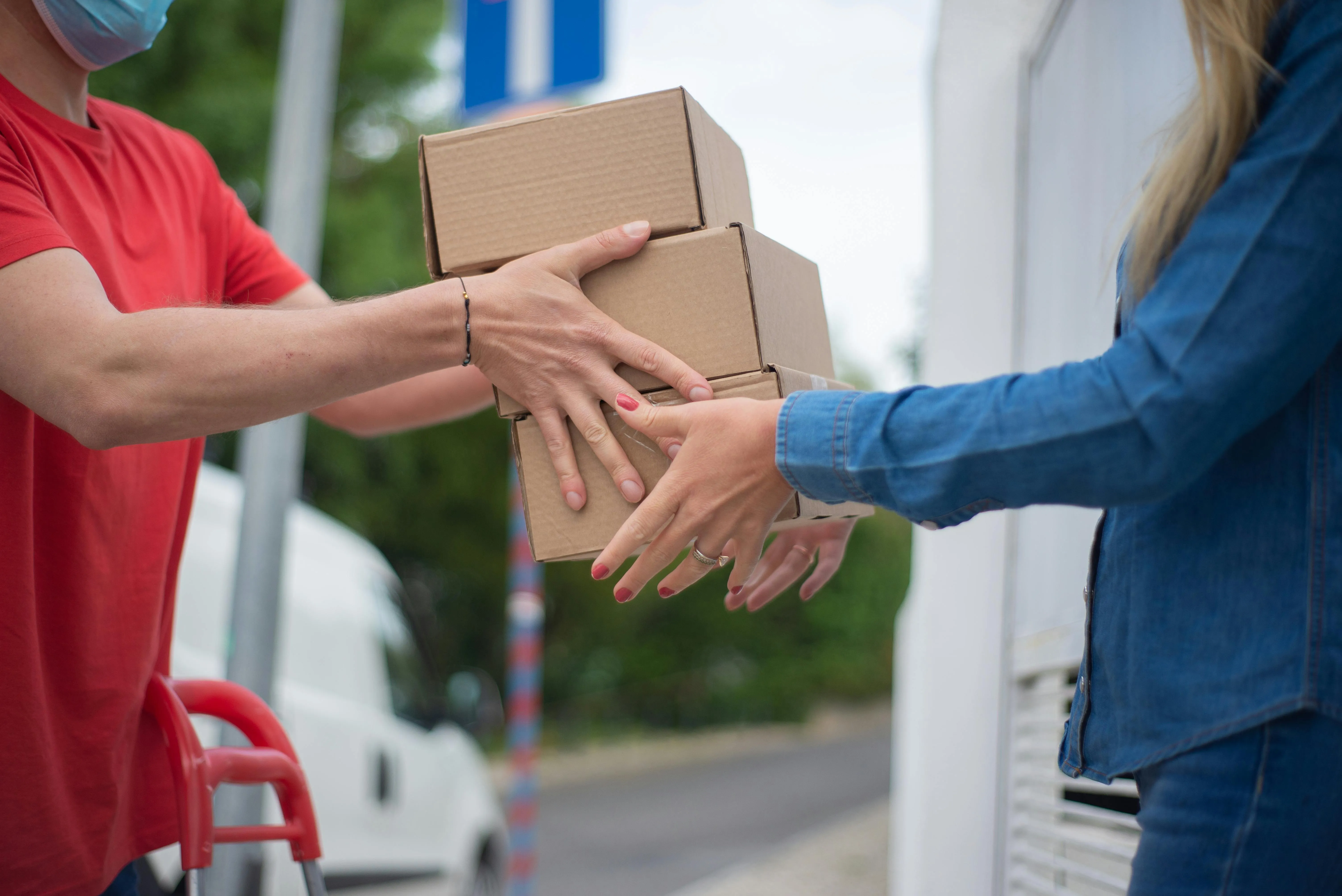 Entregador passa caixas para cliente em frente à casa
