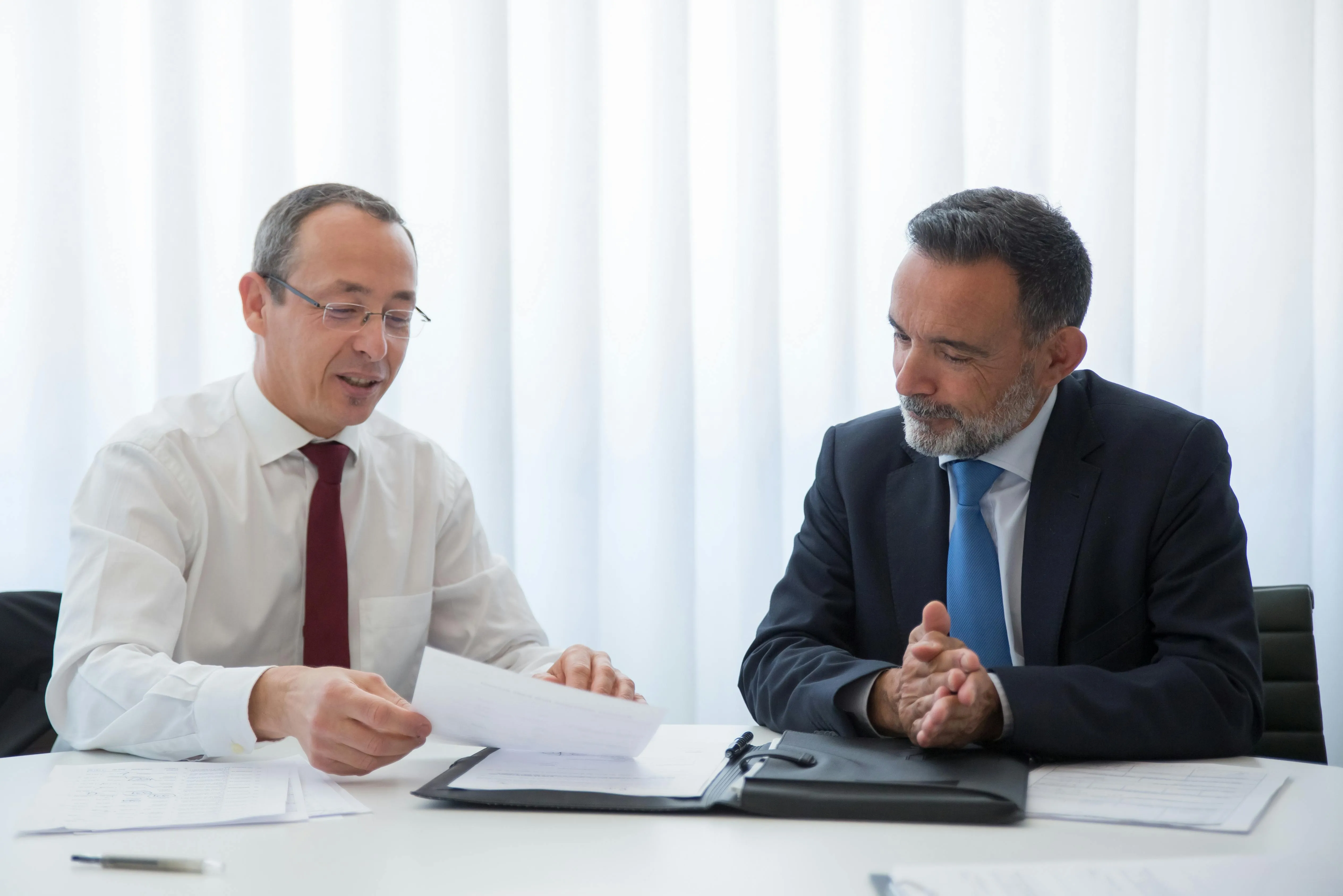 #FotoDescrição Dois homens de negócios analisando documentos em reunião.