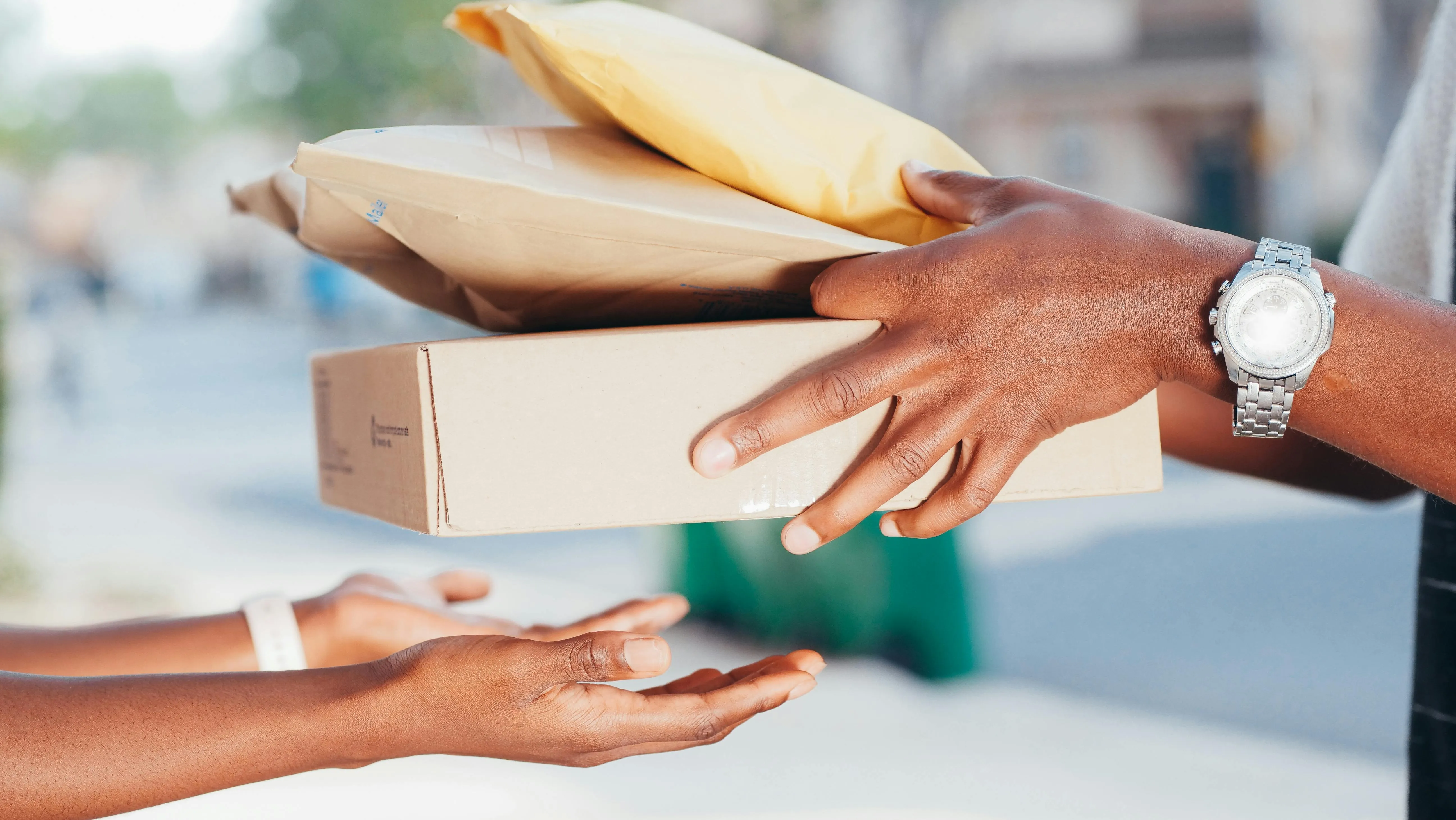 #FotoDescrição Mãos trocando pacotes em uma entrega de encomenda.