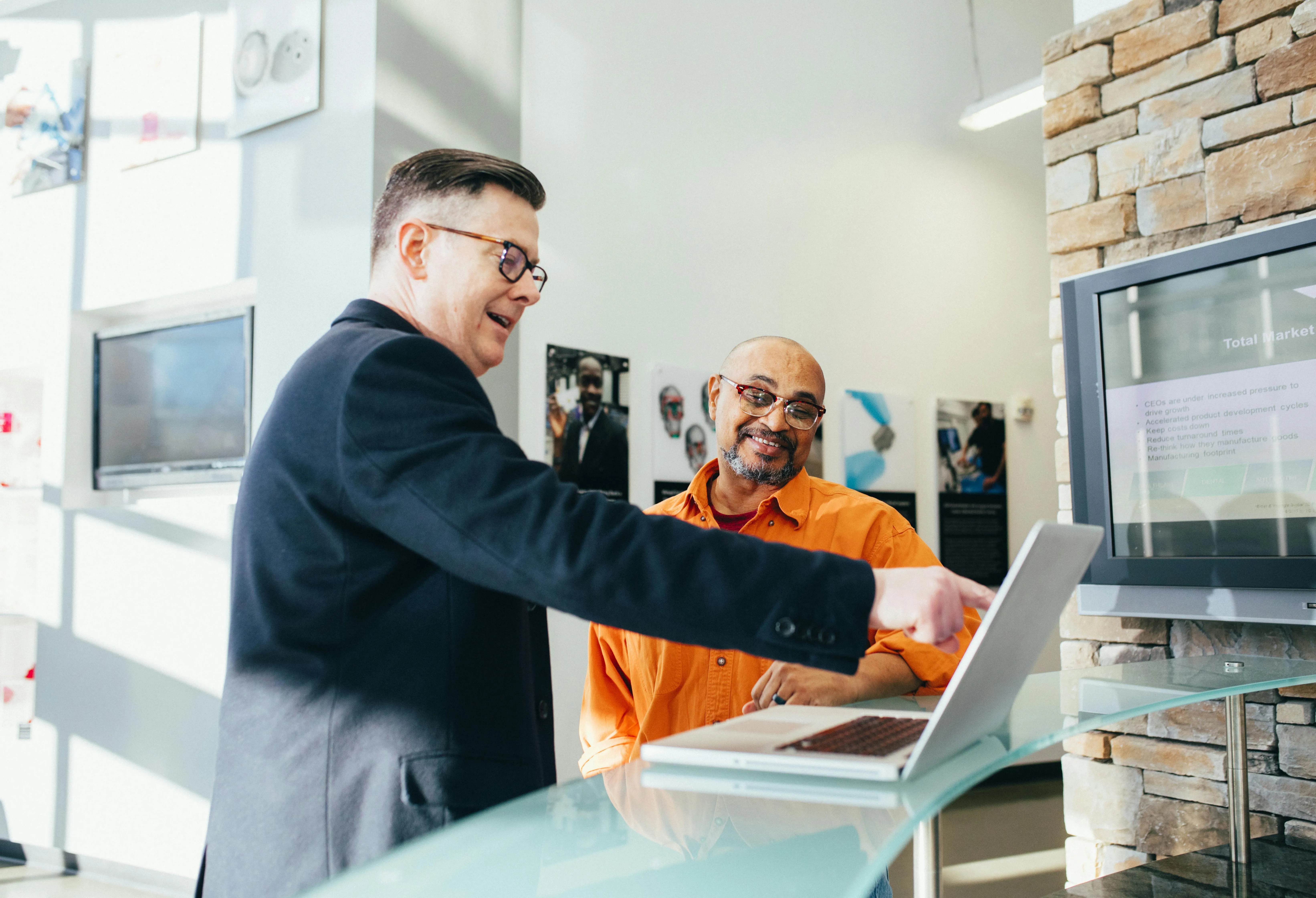 #FotoDescrição: Dois homens discutindo algo em frente a um laptop em um ambiente comercial, representando colaboração estratégica.