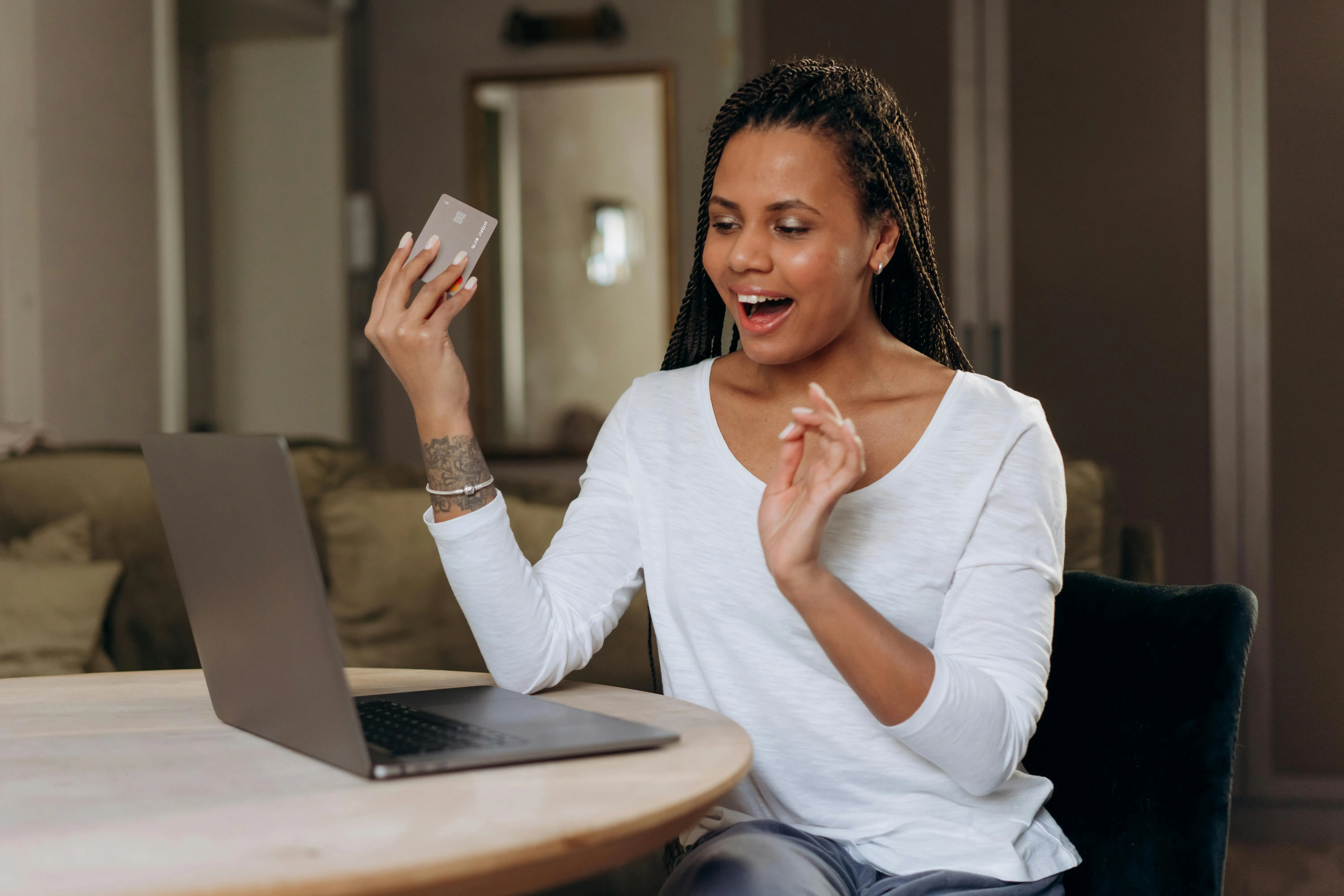 #FotoDescrição Mulher empolgada segurando um cartão e usando um laptop.