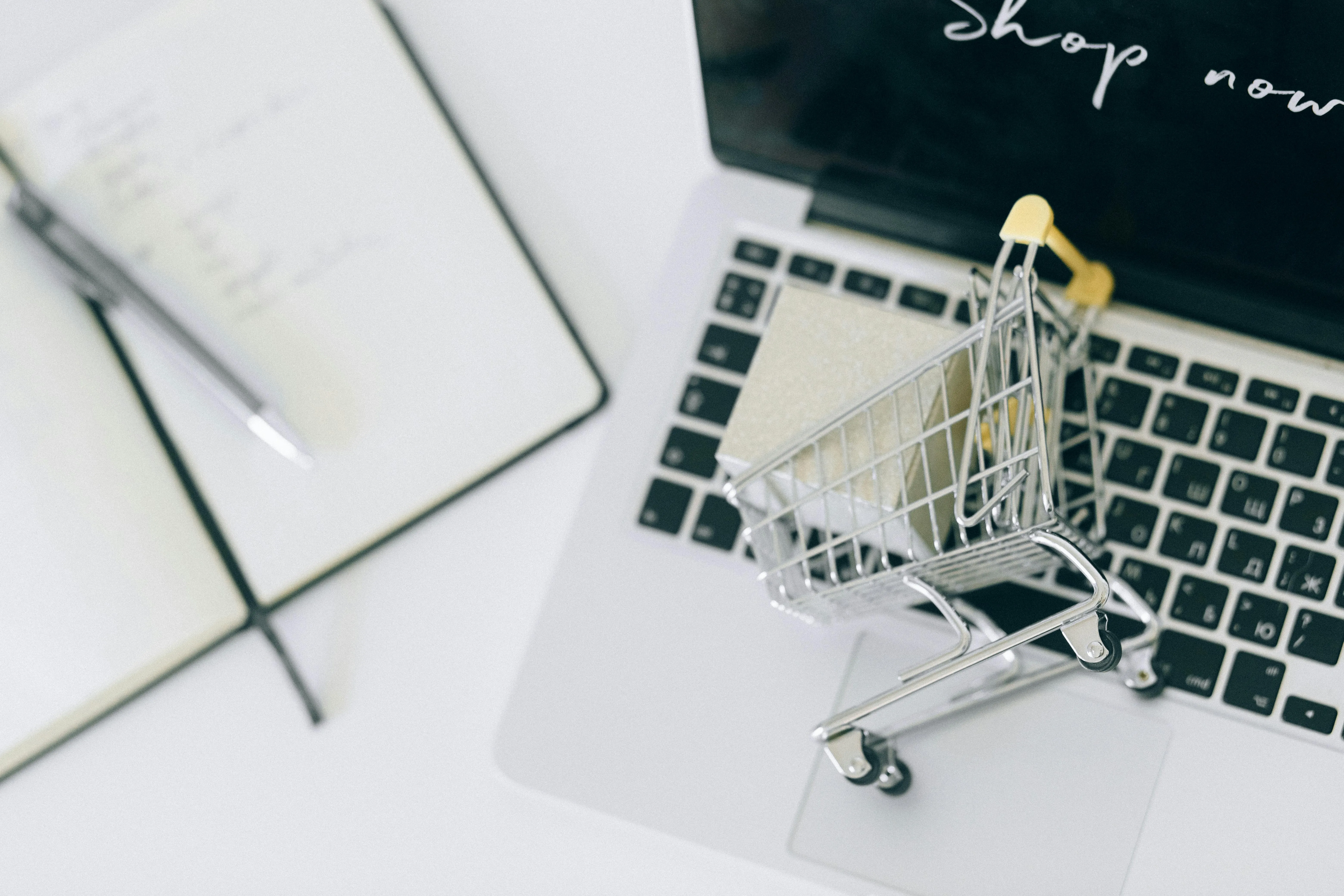 Carrinho de compras miniatura sobre notebook, conceito e-commerce
