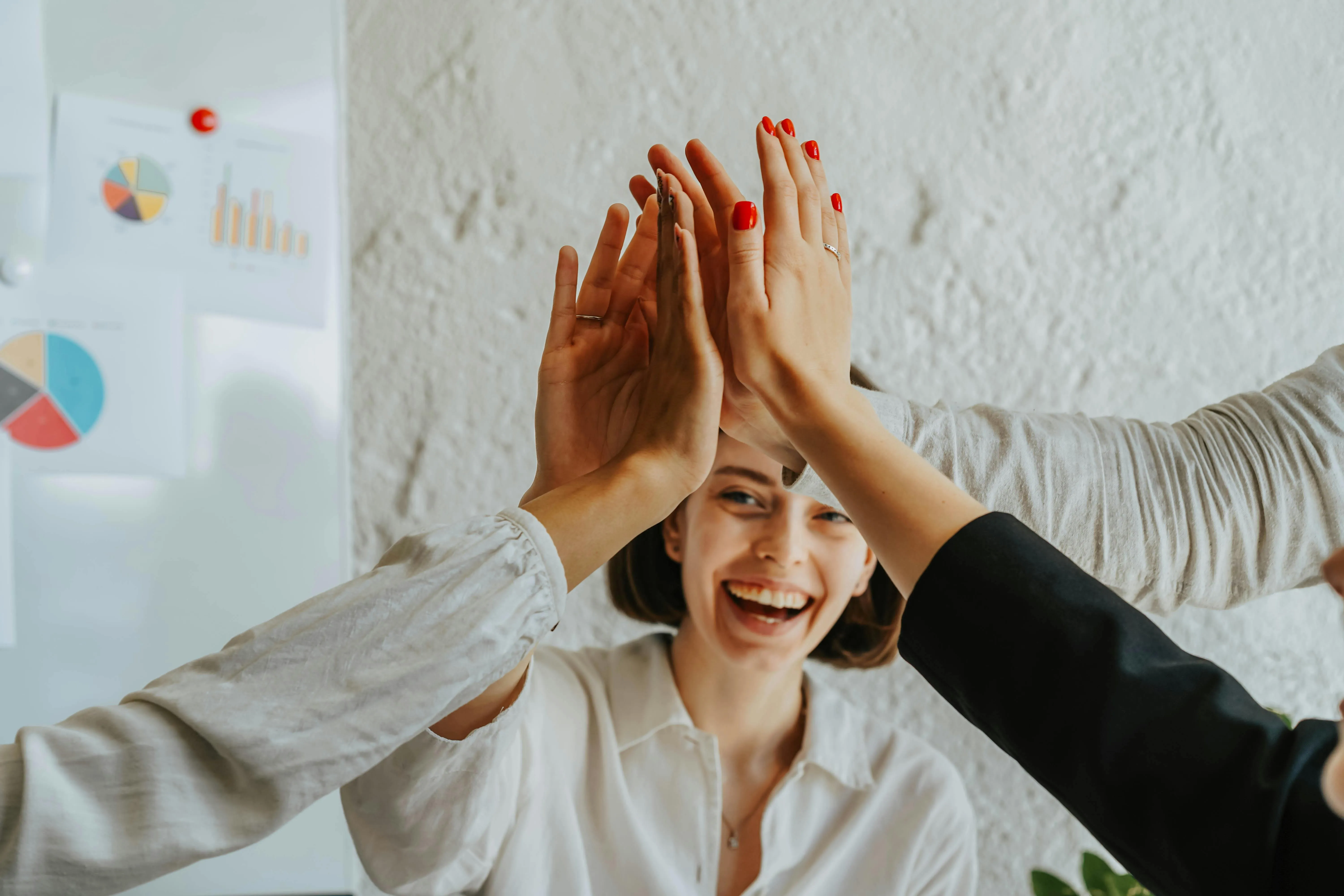 Equipe celebrando sucesso com high fives em escritório, simbolizando colaboração e conquista.