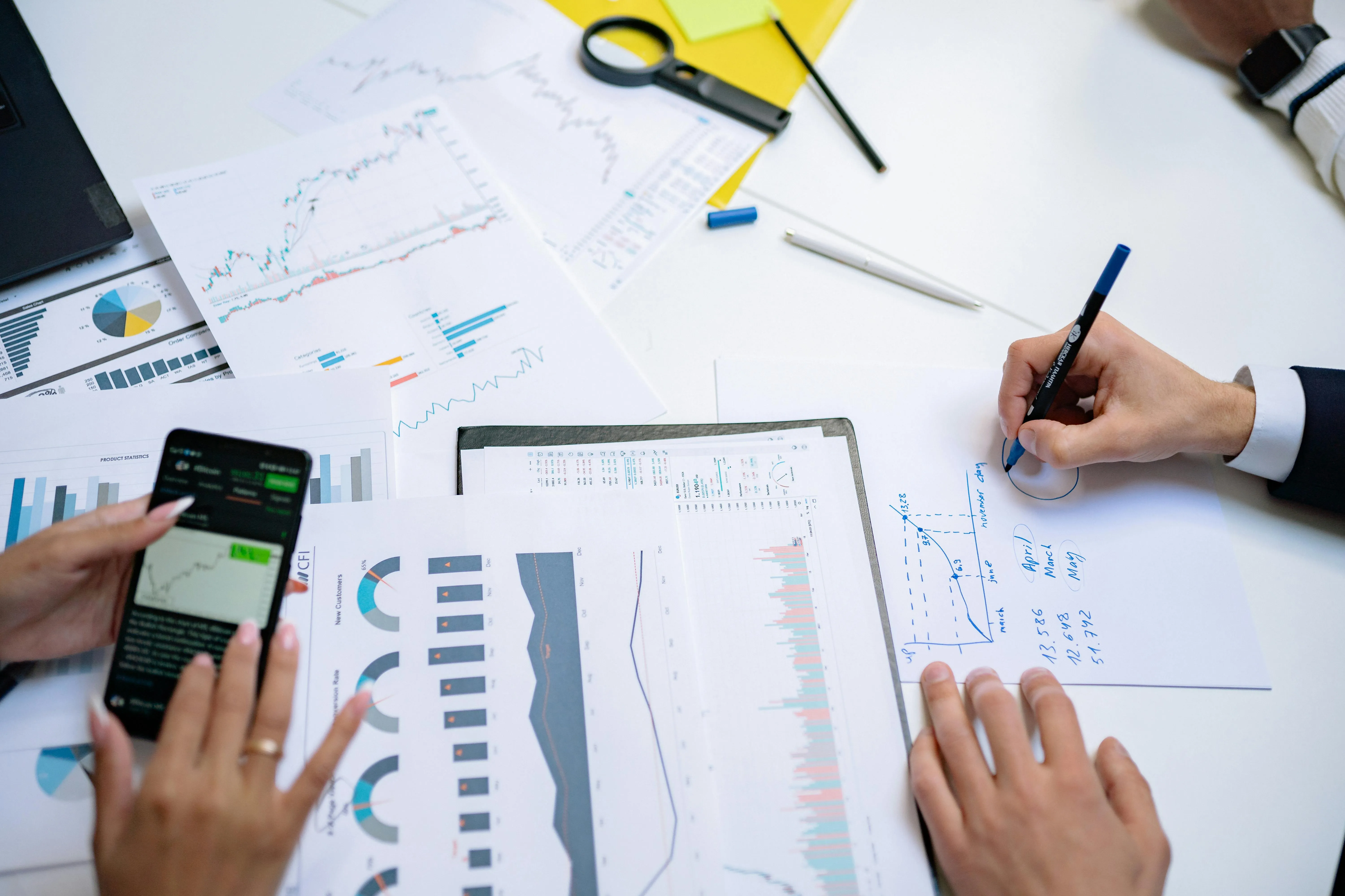 Pessoas analisam gráficos e dados em reunião de negócios com tablets e smartphones.
