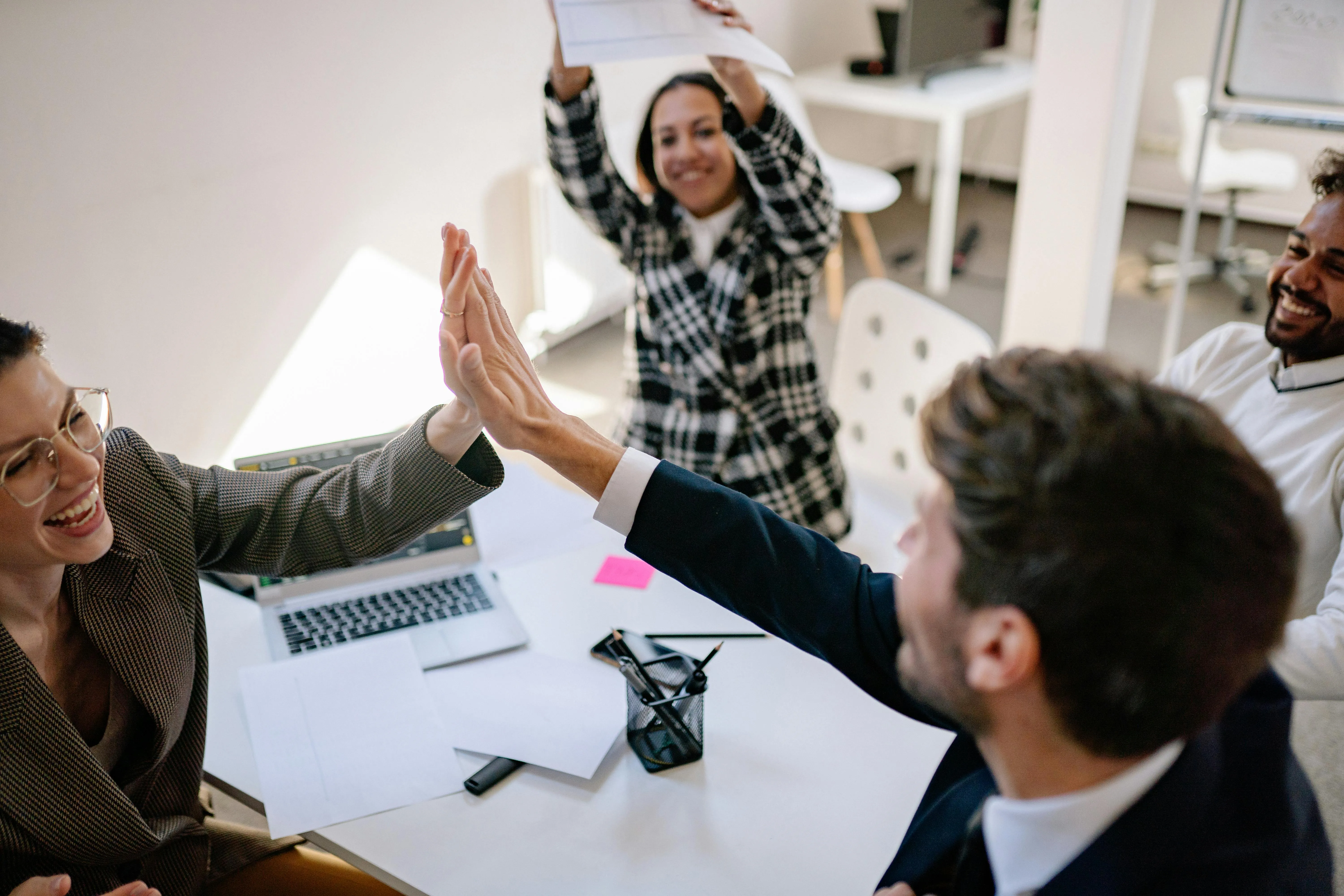 Equipe comemora sucesso com high five em reunião de escritório