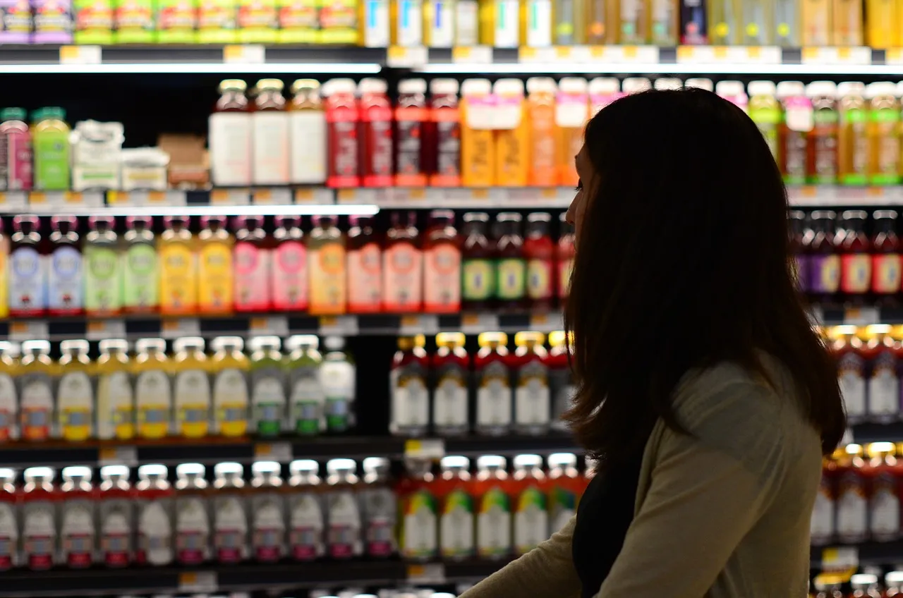 #FotoDescrição: Mulher olhando prateleiras de produtos em um supermercado, representando o processo de decisão de compra.