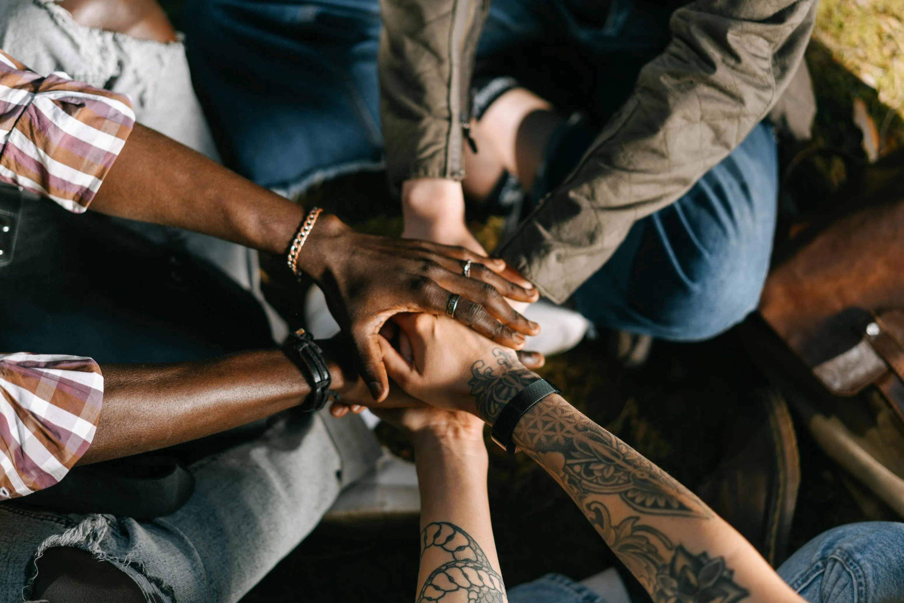 Mãos unidas de pessoas diversas simbolizando união e trabalho em equipe.
