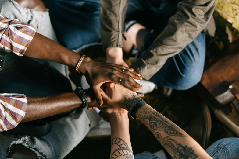 Mãos unidas de pessoas diversas simbolizando união e trabalho em equipe.