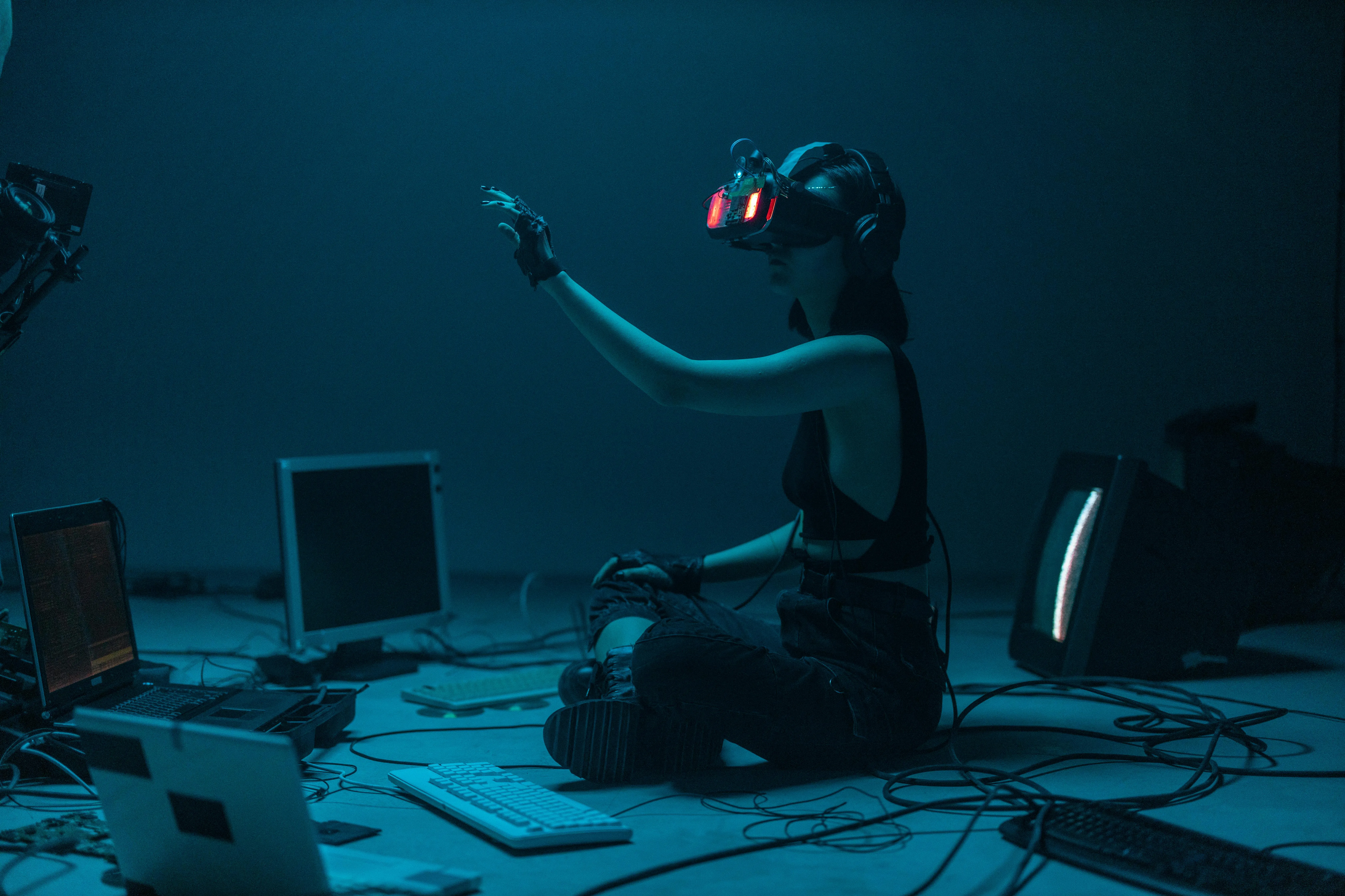 Pessoa com óculos de realidade virtual em ambiente escuro, interagindo com tecnologia digital.