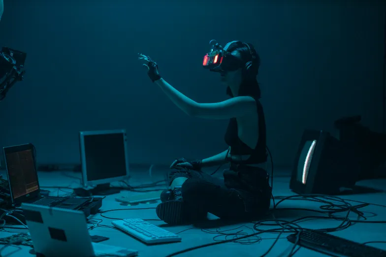 Pessoa com óculos de realidade virtual em ambiente escuro, interagindo com tecnologia digital.