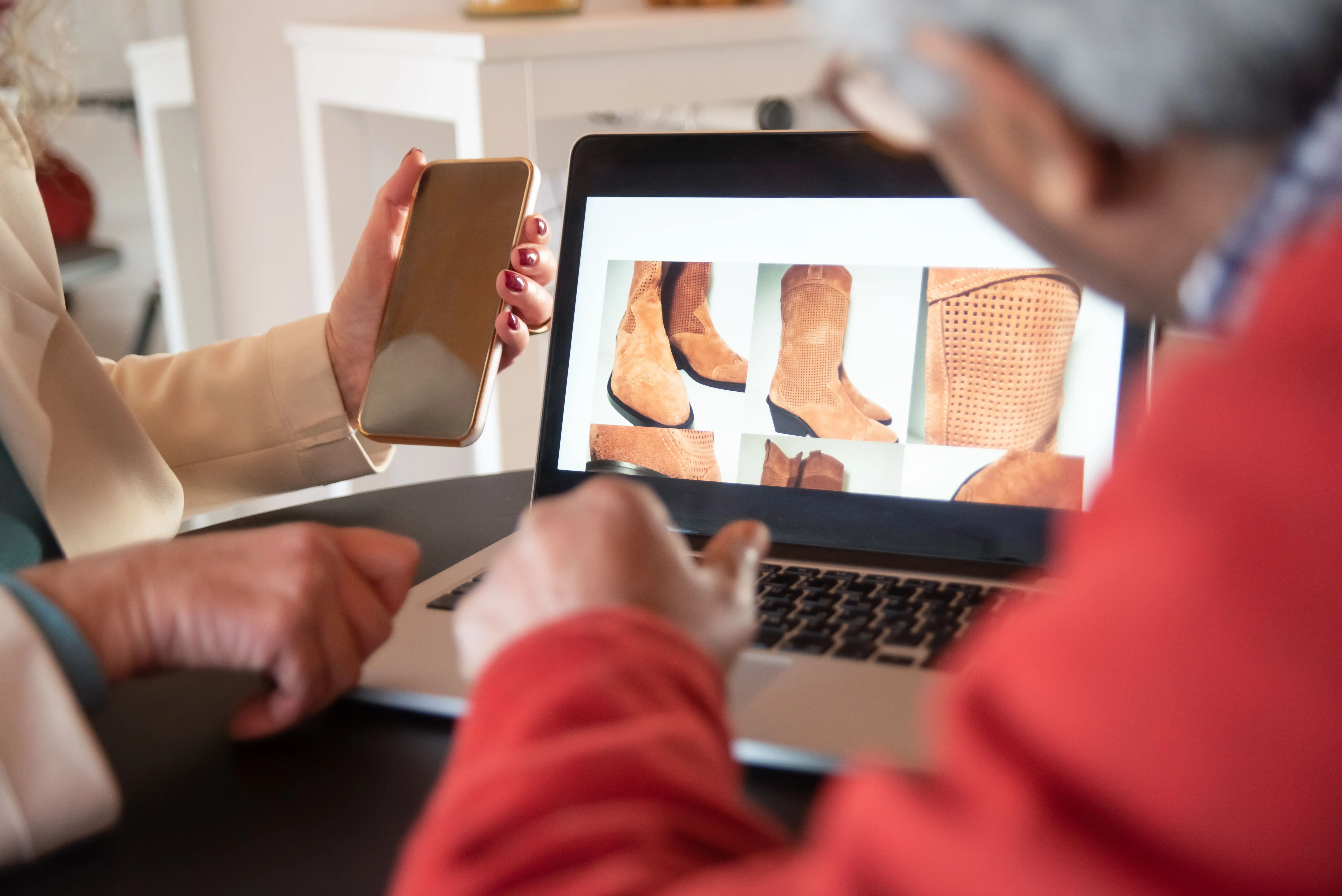 Clientes analisam botas em notebook e celular durante compra online