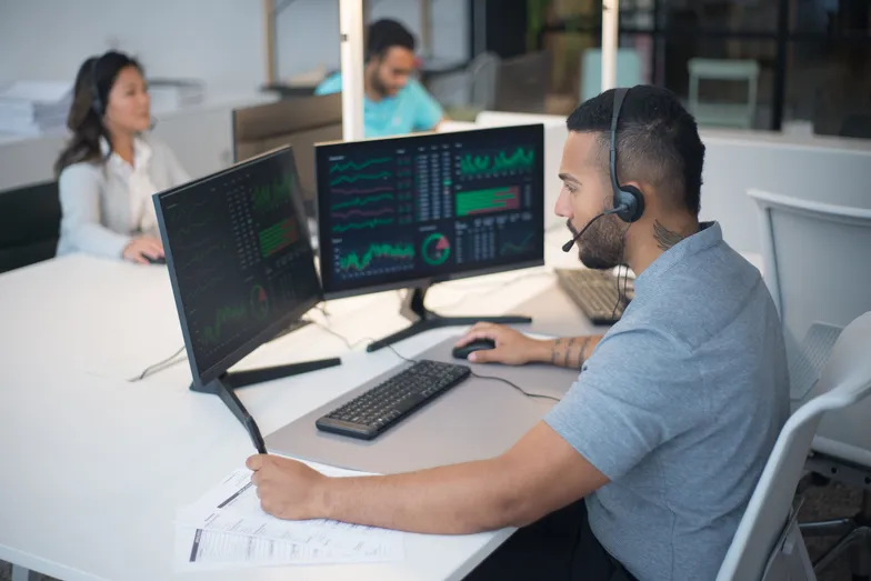 Pessoa monitora dados em telas durante atendimento em escritório.