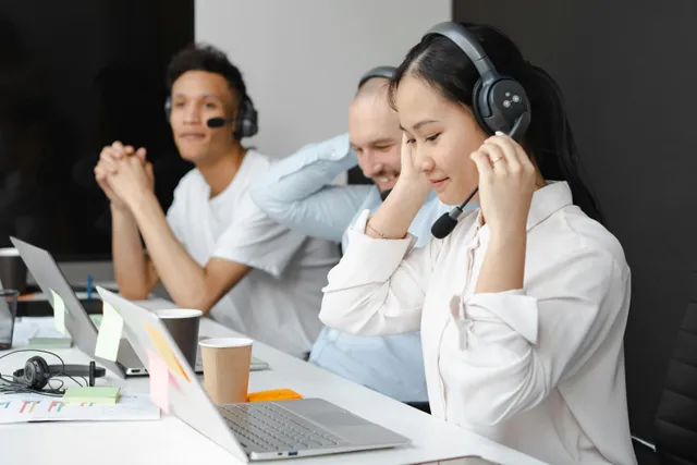 Equipe de suporte usando headsets e trabalhando em laptops.