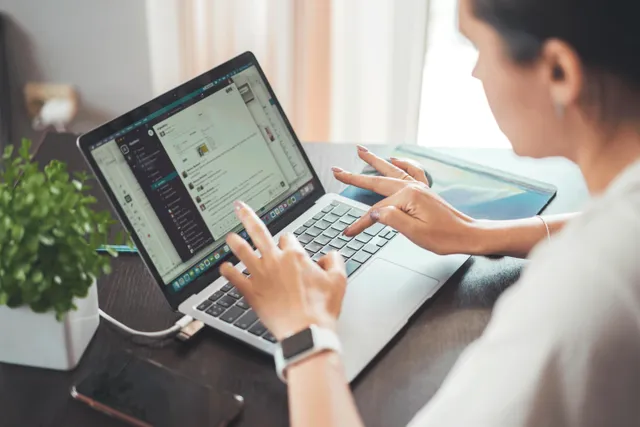 Pessoa trabalhando em laptop com aplicativo aberto na tela.