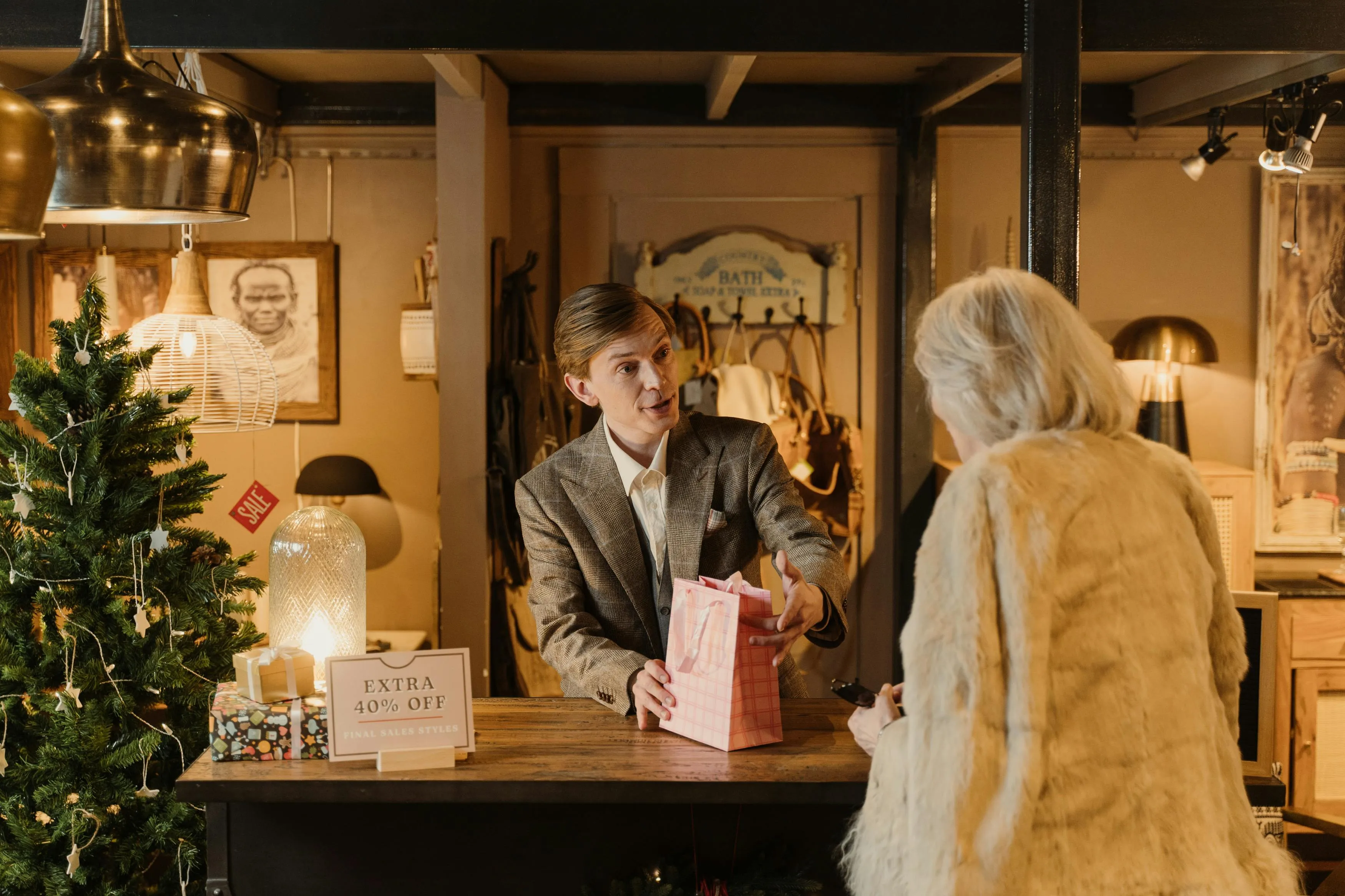 Vendedor entrega sacola de presente a cliente em loja decorada para Natal.