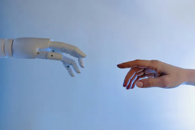 Mão robótica e mão humana quase se tocando, simbolizando conexão humano-IA