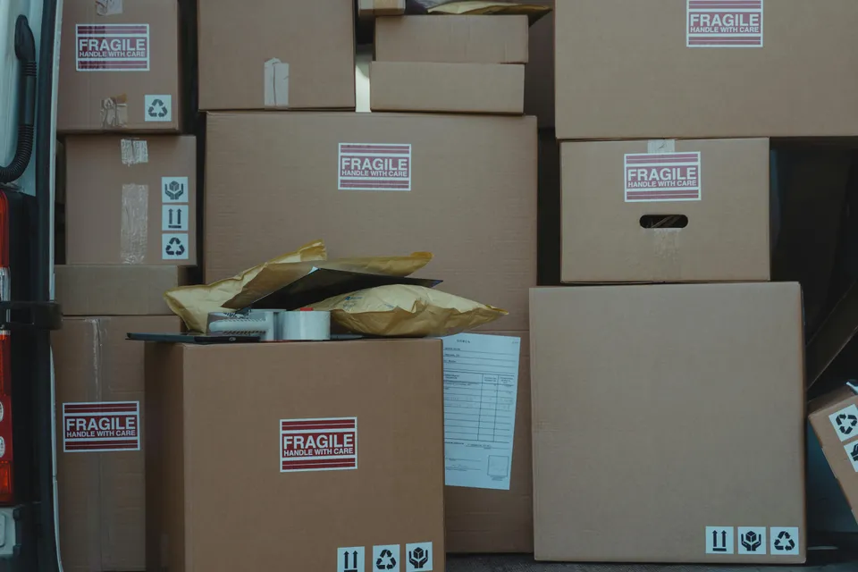 Caixas de papelão empilhadas com etiquetas “frágil” em caminhão