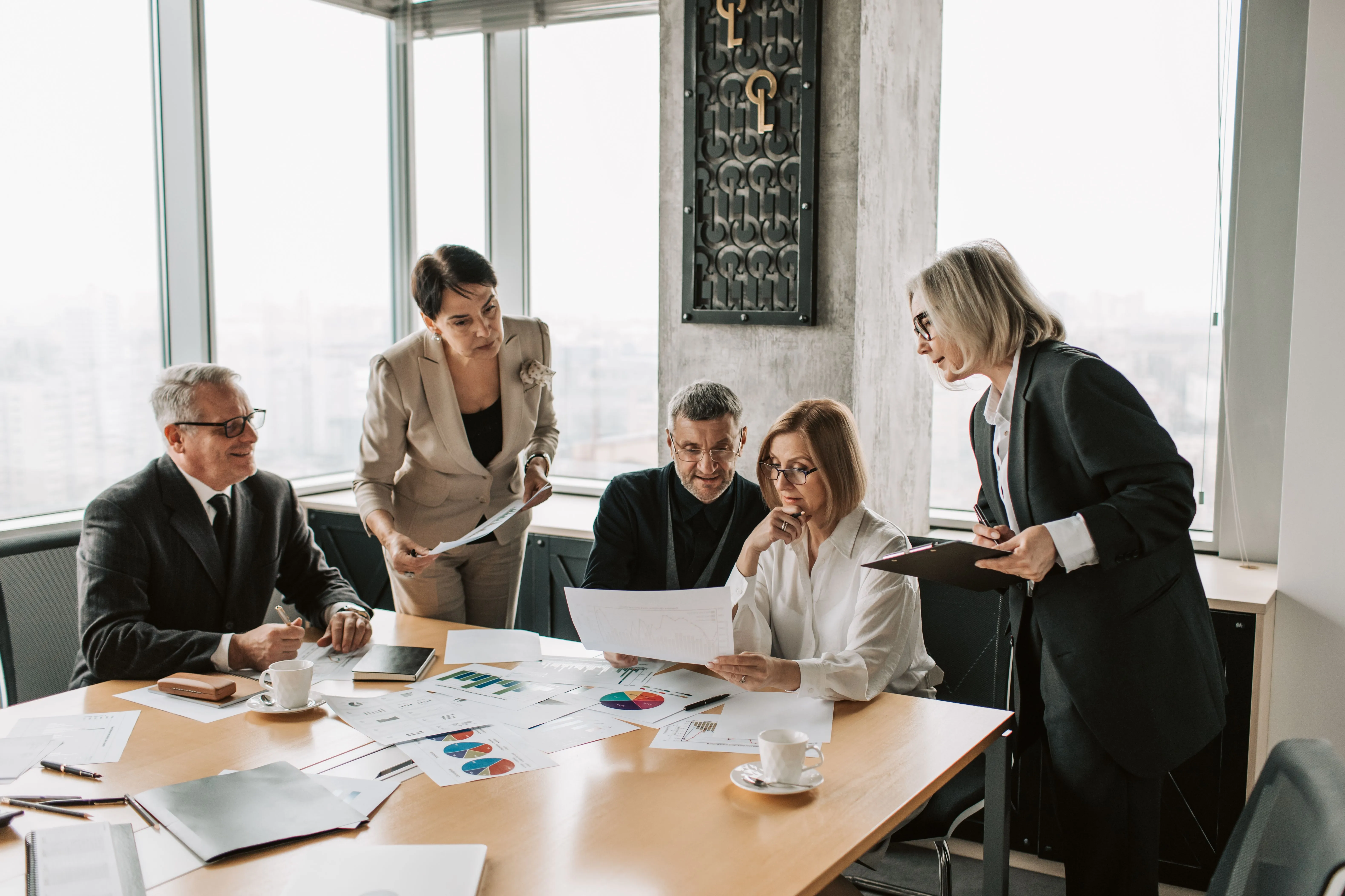 Executivos analisam gráficos e documentos durante reunião empresarial.