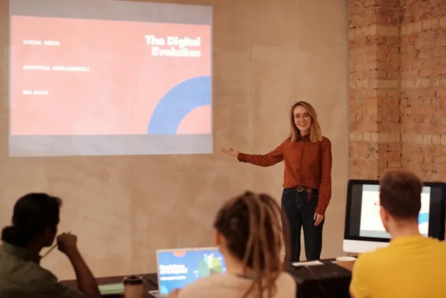 Mulher apresenta palestra sobre transformação digital em evento com público e parede de tijolos.