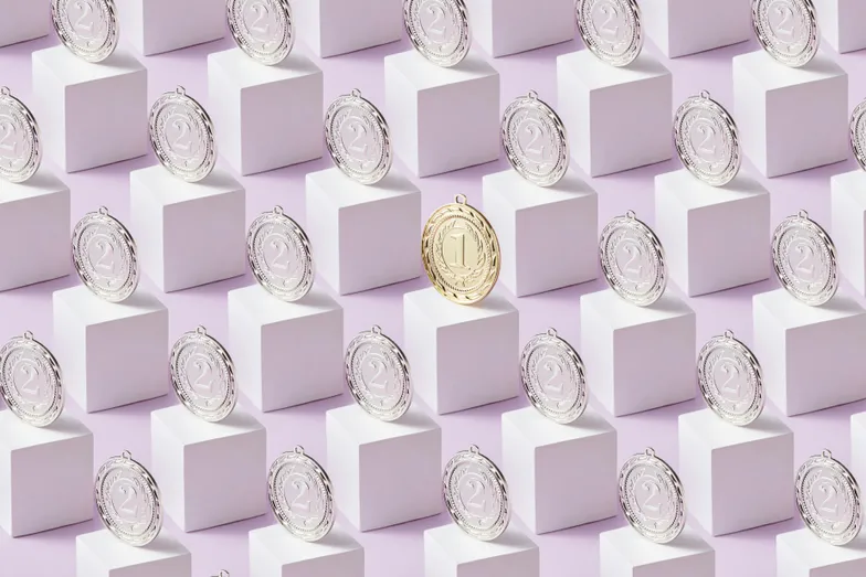 Medalhas prateadas e uma dourada destacada sobre blocos geométricos