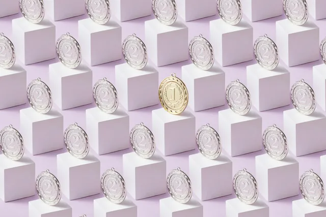 Medalhas prateadas e uma dourada destacada sobre blocos geométricos