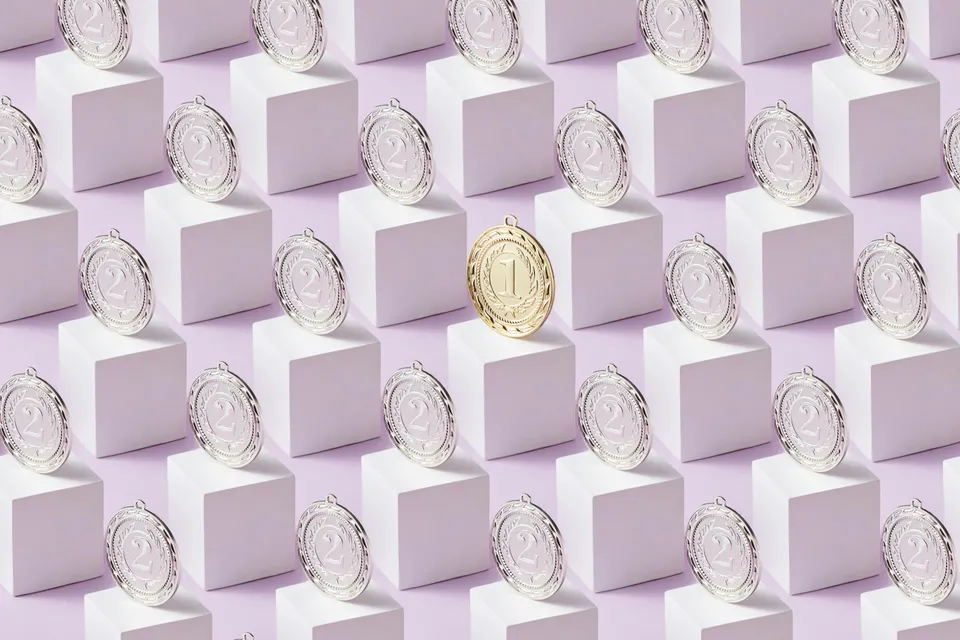 Medalhas prateadas e uma dourada destacada sobre blocos geométricos