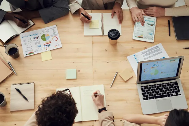 #FotoDescrição: Pessoas reunidas em uma mesa de trabalho, analisando gráficos e planejando estratégias de negócios.