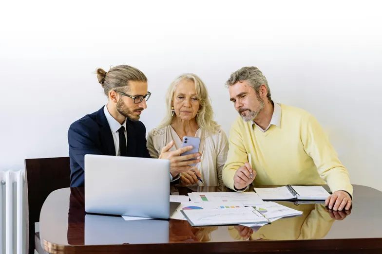 #FotoDescrição Consultor explicando informações financeiras para casal em reunião.