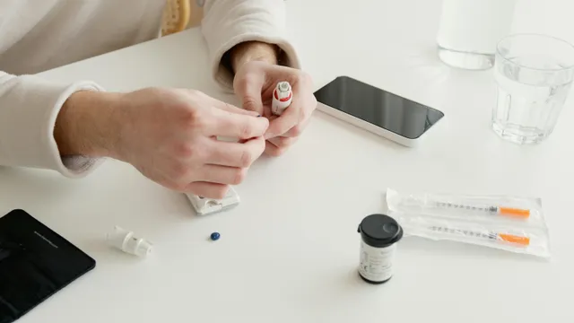 Mãos manipulando caneta de insulina sobre mesa com seringas e remédios.