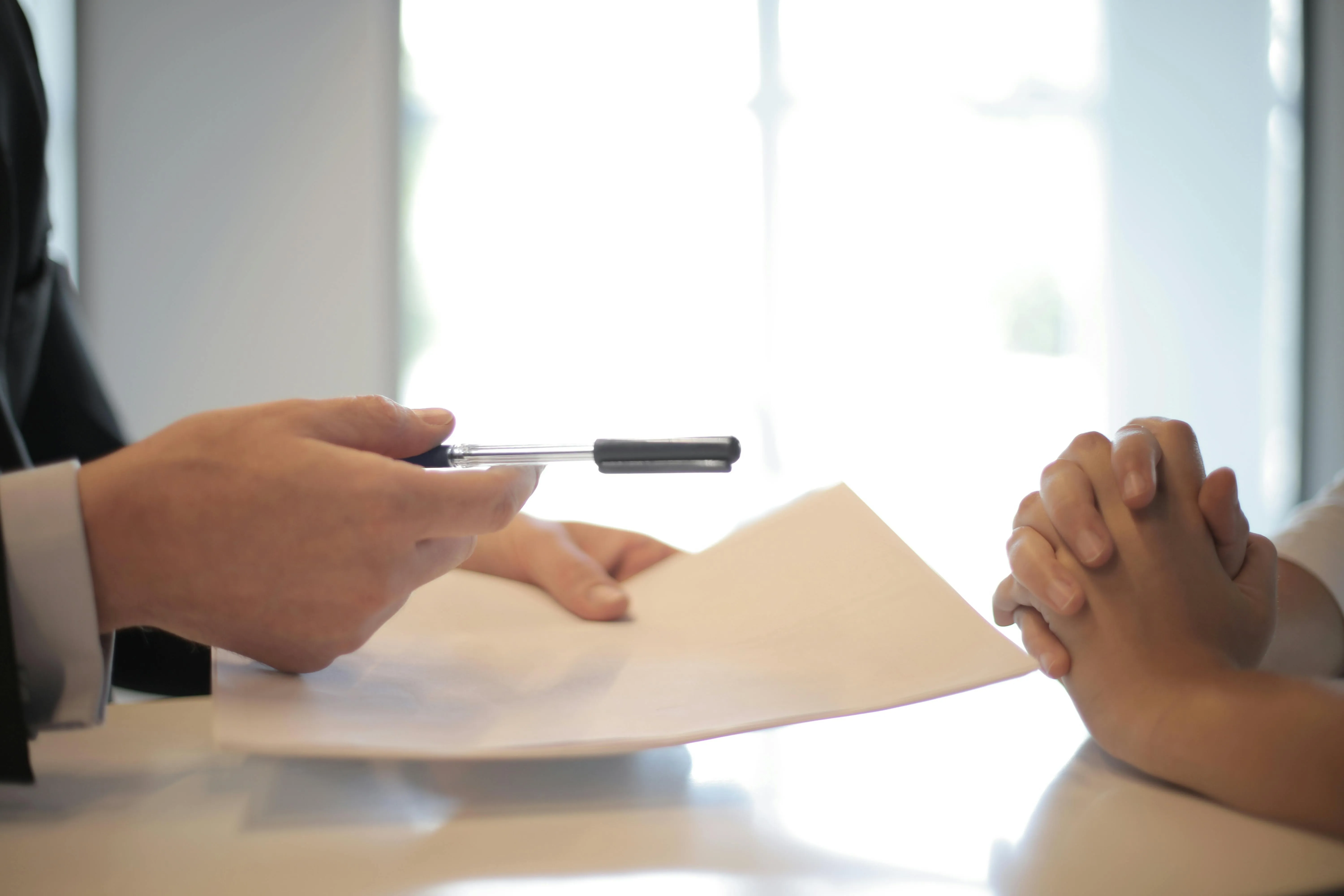 #FotoDescrição: Pessoa entregando uma caneta para assinatura de documento, representando transparência e confiança nos negócios.