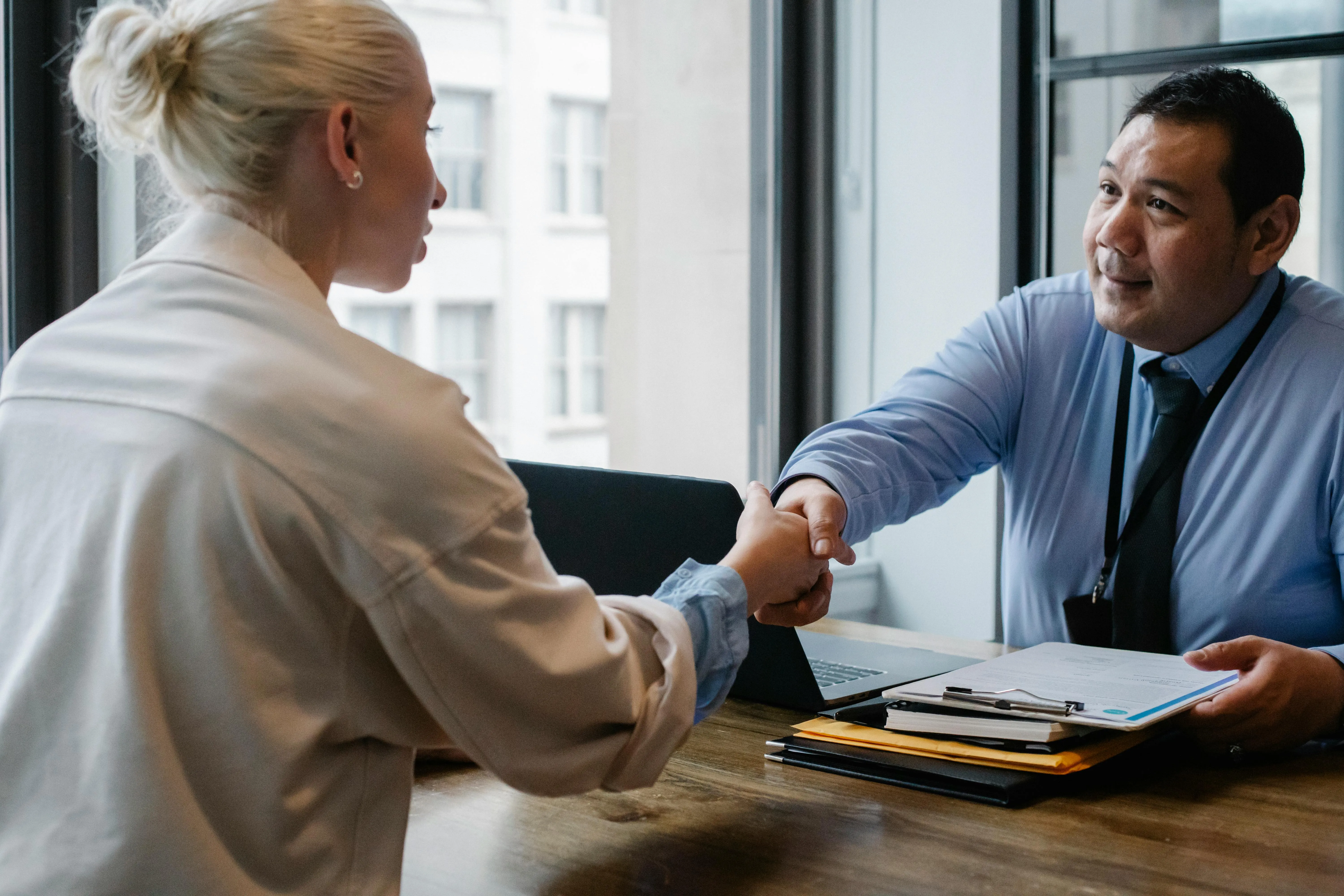 #FotoDescrição: Profissional apertando a mão de cliente em reunião, simbolizando confiança e parceria.