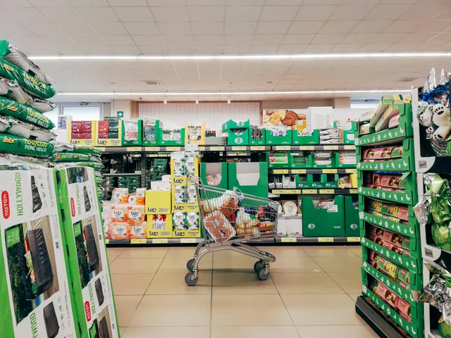Corredor de supermercado com prateleiras cheias e carrinho no centro