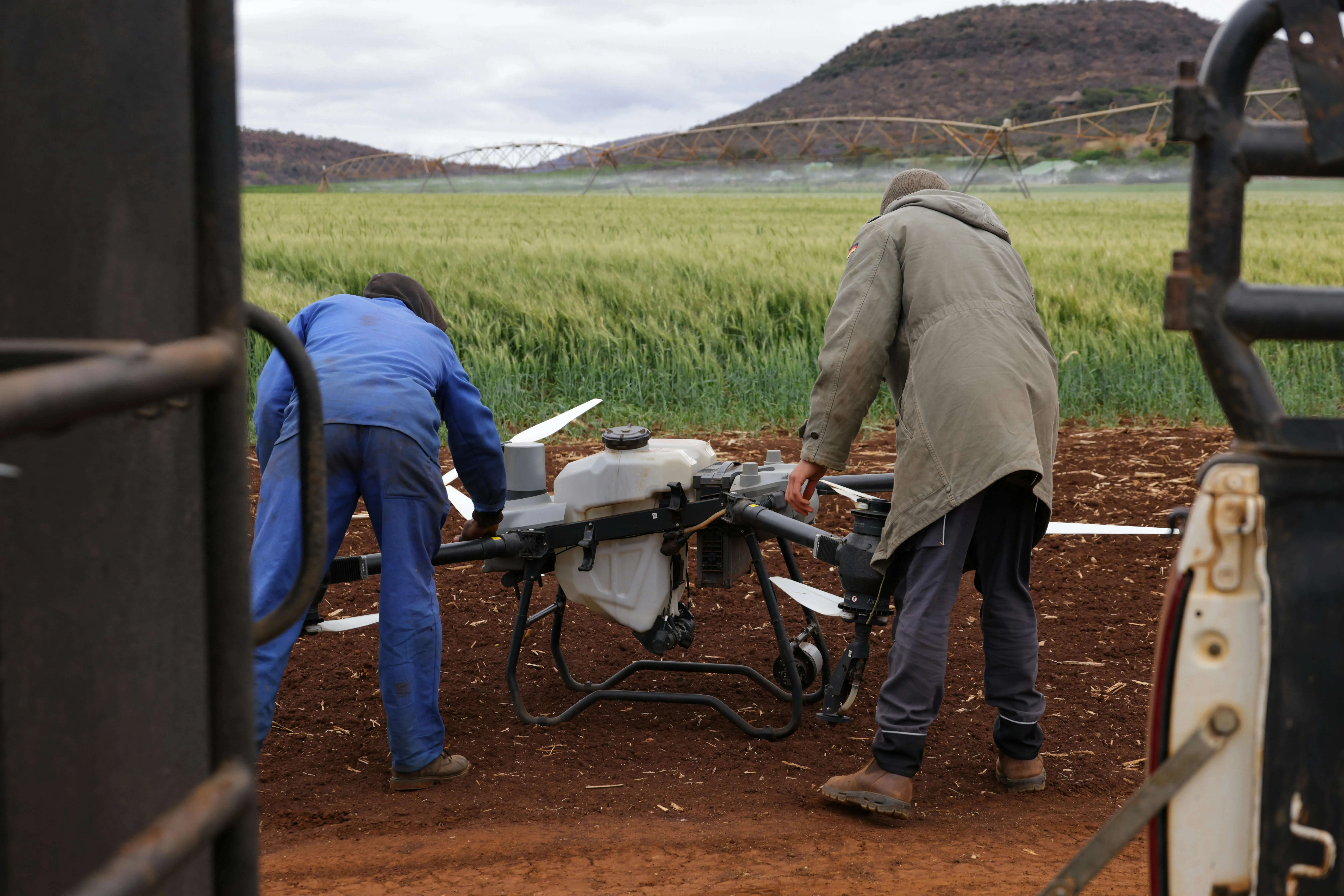 Trabalhadores preparam drone agrícola em campo de cultivo