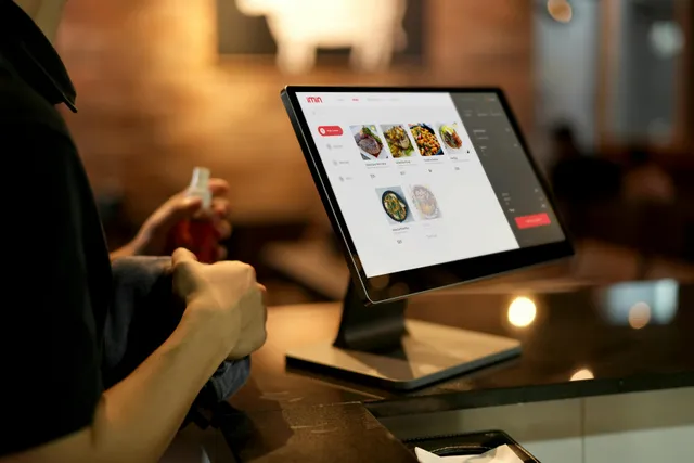 Pessoa fazendo pedido online em restaurante via computador na mesa.