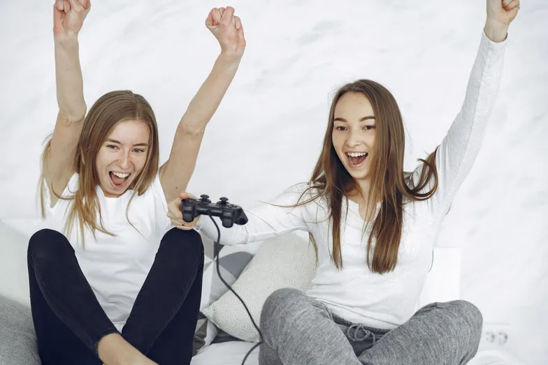 Duas mulheres comemorando vitória em videogame com controle nas mãos