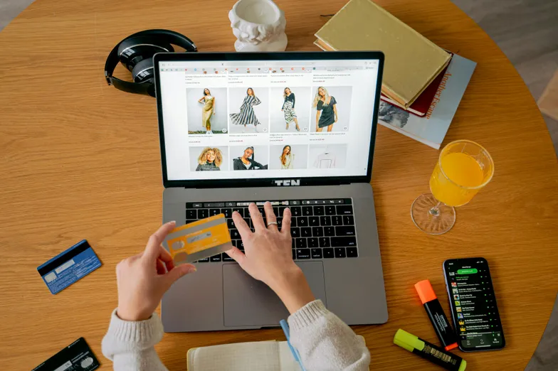 Pessoa comprando roupas online no notebook com cartão em mãos