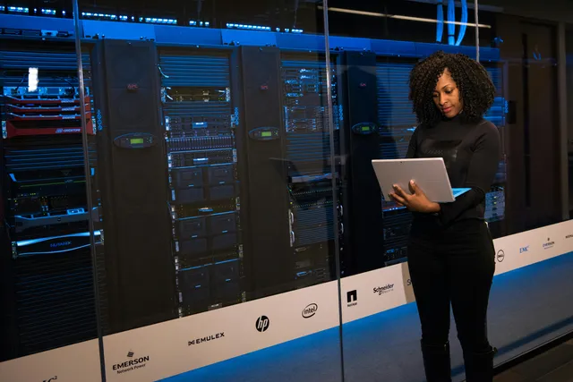 Profissional analisando equipamentos de servidor em data center, foco em rede e tecnologia.