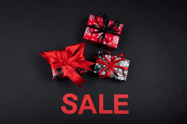 Caixas de presente decoradas sobre fundo preto com a palavra sale.