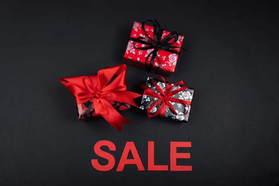 Caixas de presente decoradas sobre fundo preto com a palavra sale.