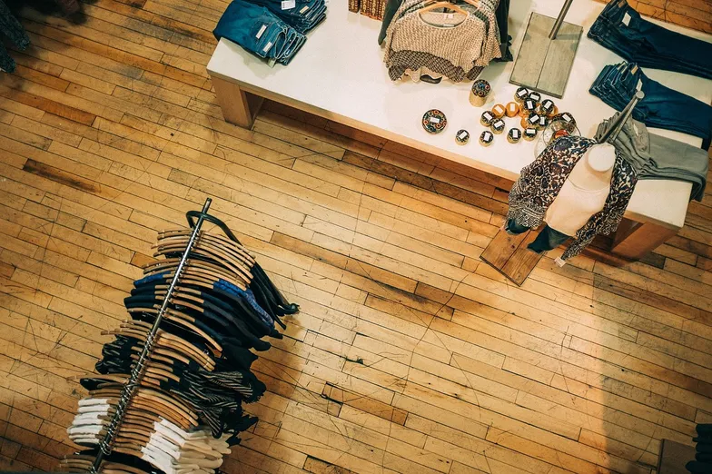 #FotoDescrição Loja de roupas vista de cima, com araras e uma mesa de exposição.