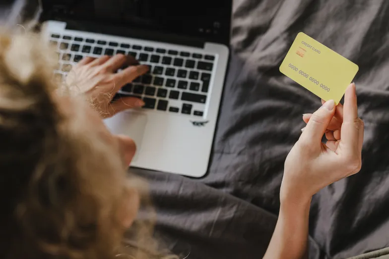 Pessoa faz compra online usando cartão de crédito e notebook.