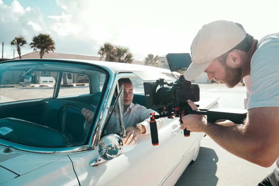 Cinegrafista filma homem dentro de carro clássico em gravação externa